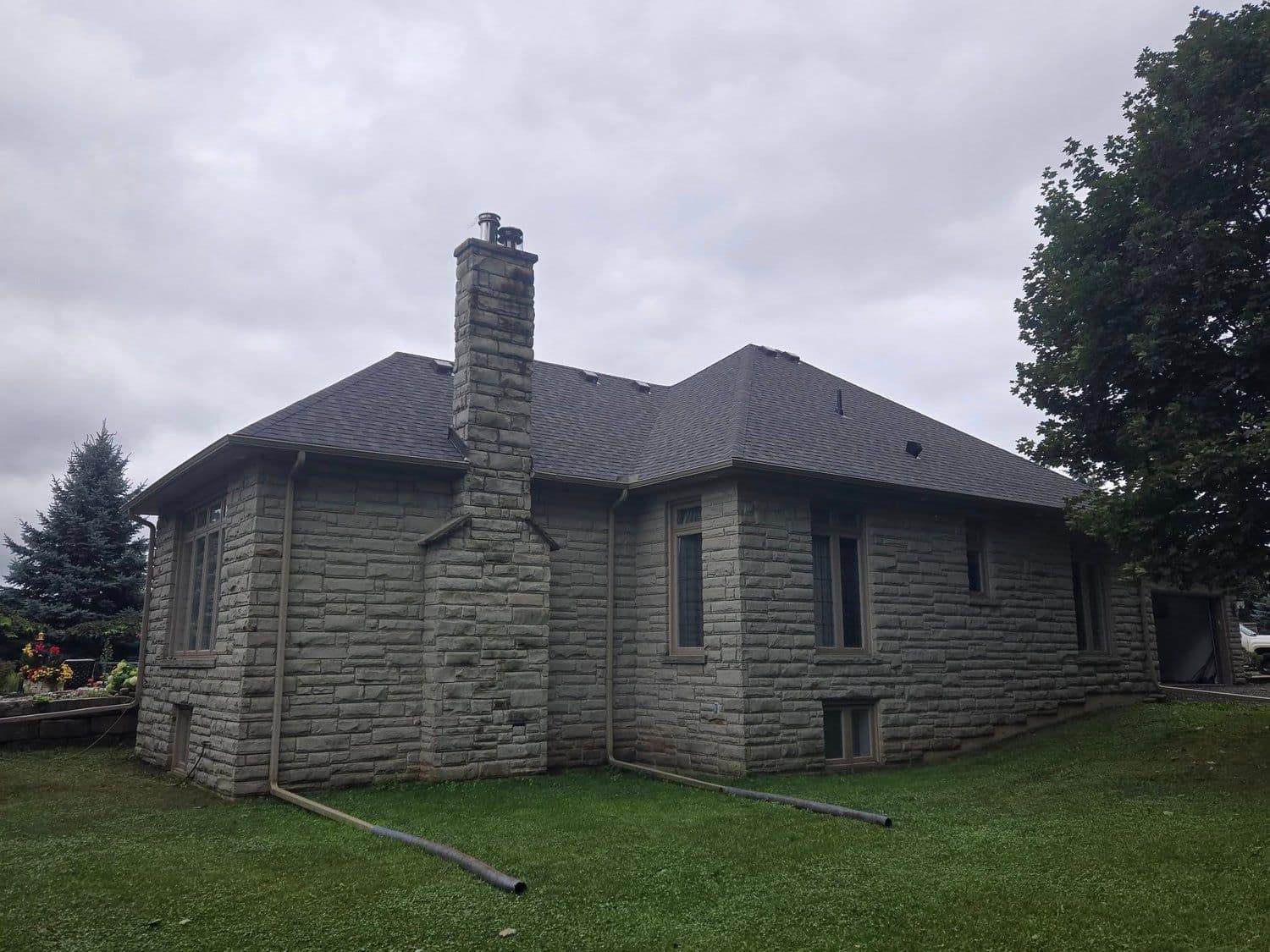 Completed shingle roof on a stone home under a dramatic sky