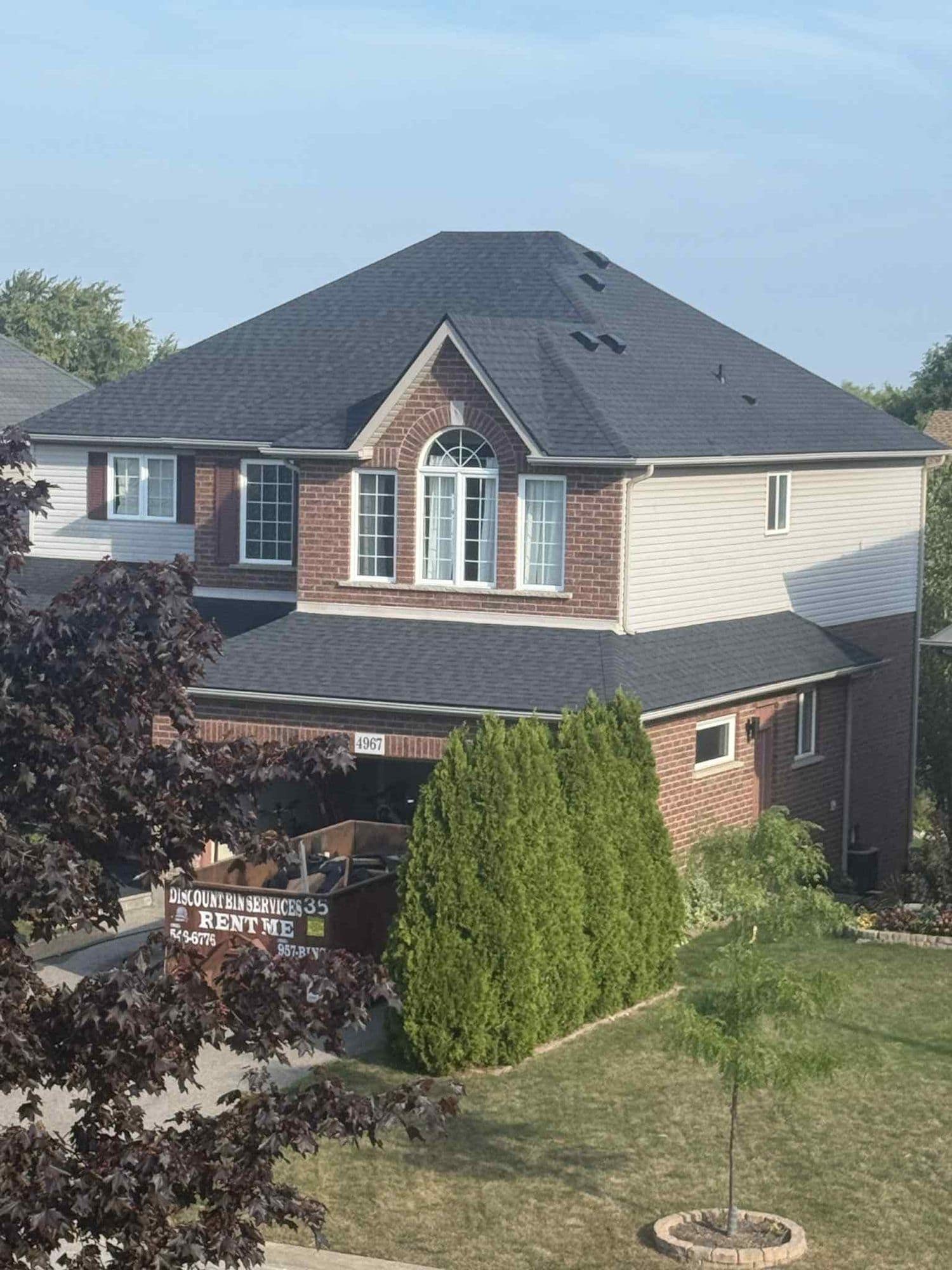 Two-storey brick home with a new dark shingle roof