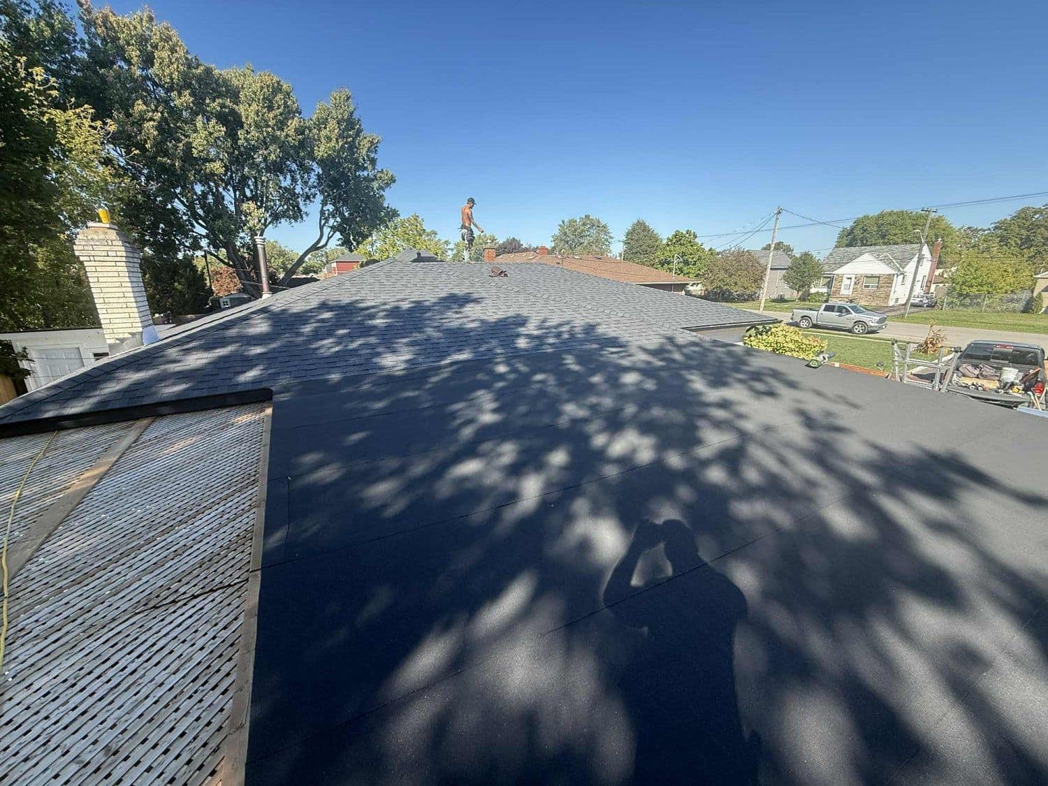 Close-up of freshly installed charcoal shingles against a blue sky